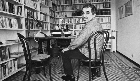 Gabriel Garcia Marquez sentando delante de muchos libros