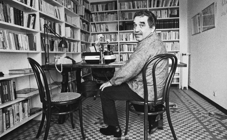 Gabriel Garcia Marquez sentando delante de muchos libros